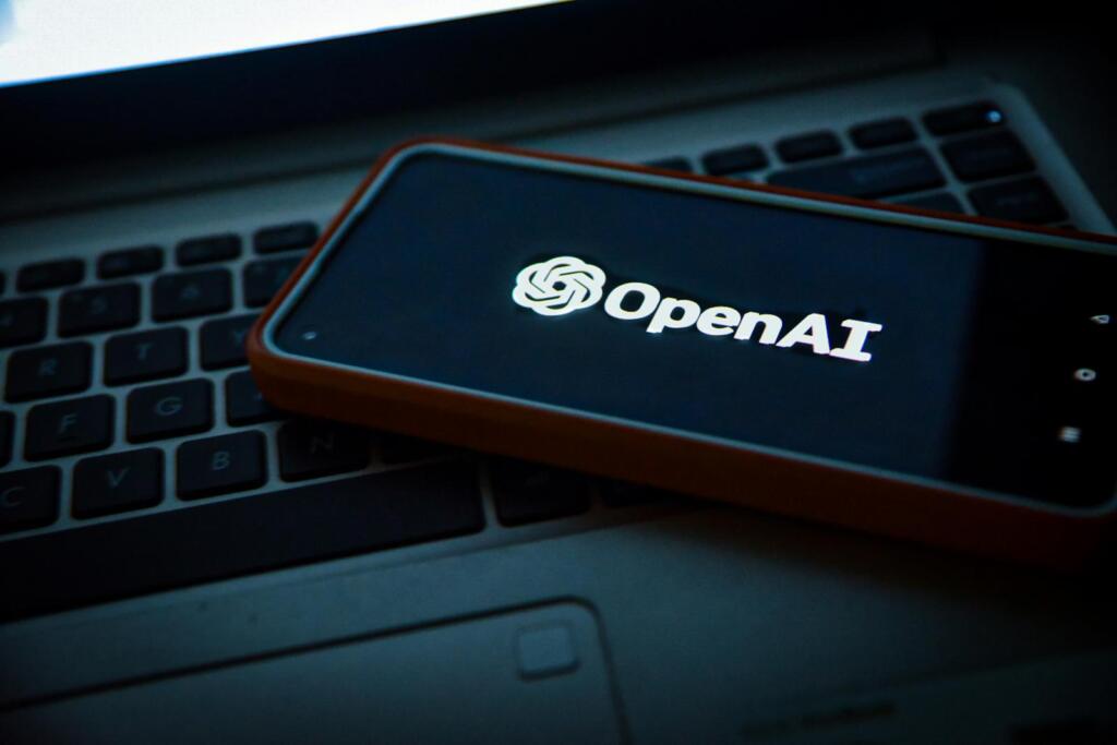 OpenAI logo displayed on a smartphone screen placed on a laptop keyboard. ChatGPT shopping features for eCommerce brands.